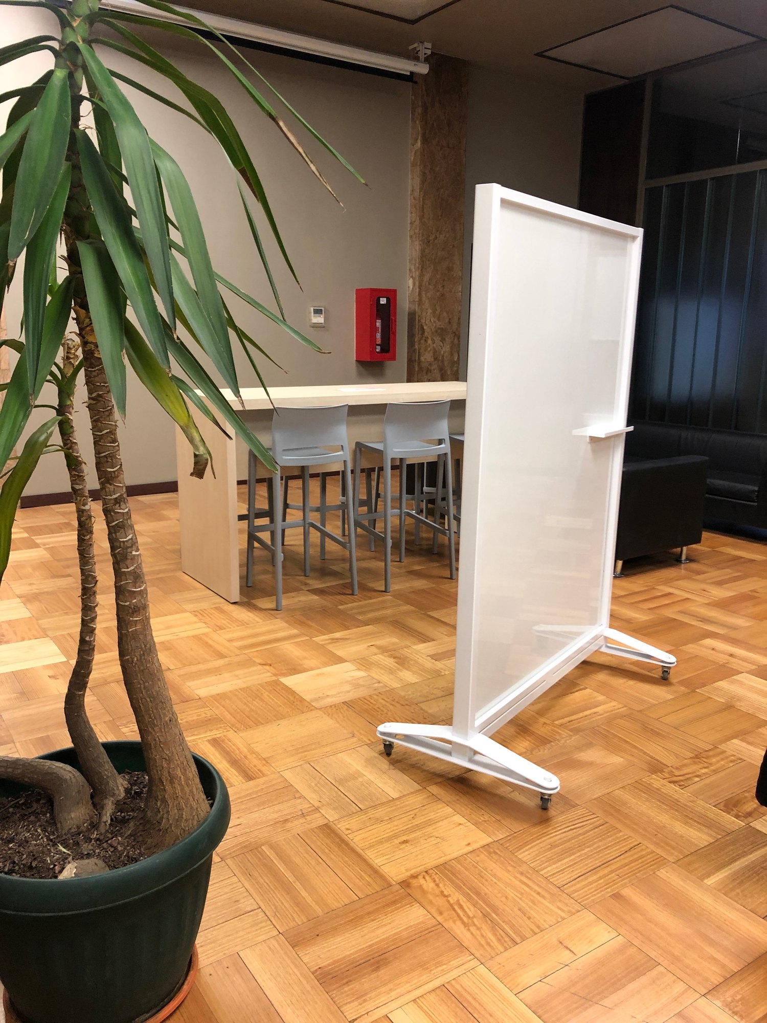 Biombo blanco con base móvil junto a una mesa alta y una planta