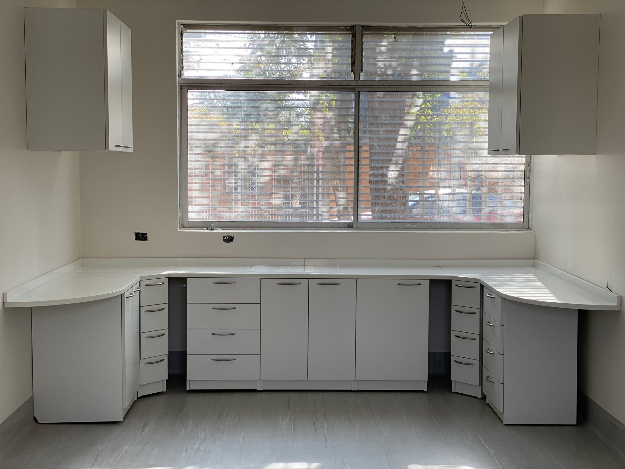 Mobiliario blanco con cubierta continua y cajoneras junto a una ventana